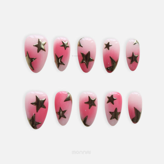 Blush Star press-on nails in pink gradient with metallic bronze stars, shown as a laid-out set on white