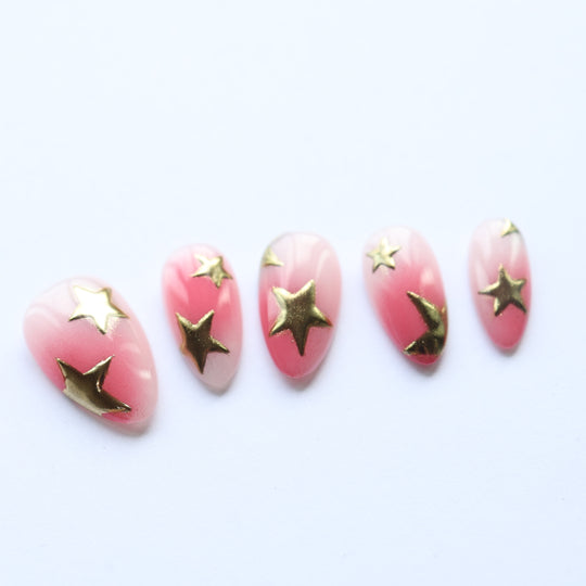Blush Star press-on nails laid out with pink gradient and metallic gold star accents