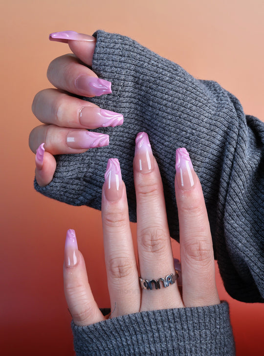 Blush Swirl press-on nails worn on hands, soft pink nude fade with raised gel tips and a clean minimal look.