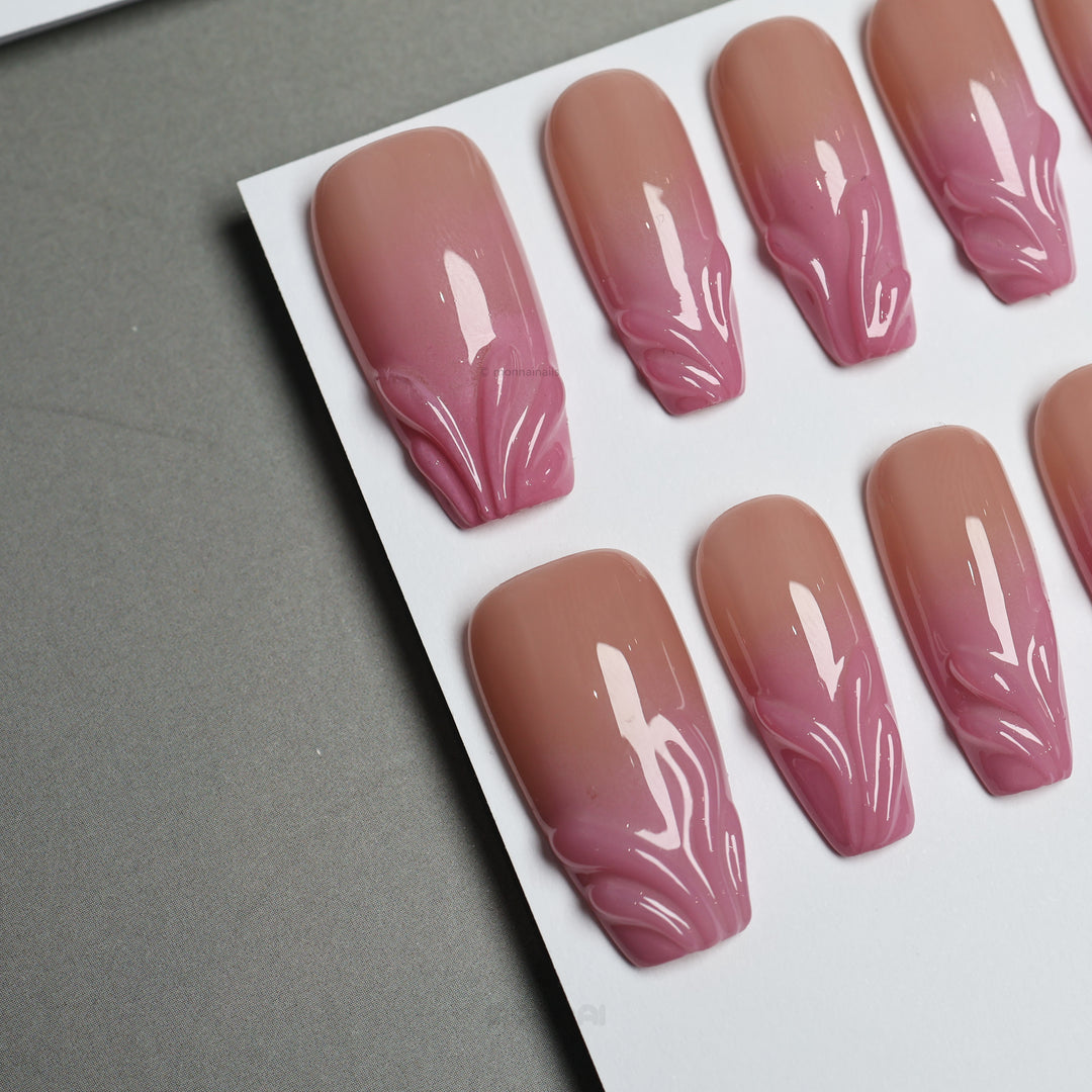 Blush Swirl press-on nails laid out with nude-to-pink fade and raised gel tips