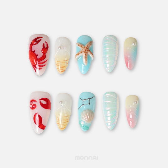 Cancer press on nails from the Zodiac Collection, featuring pastel ocean tones, crab motifs, seashells, pearls and constellation details.