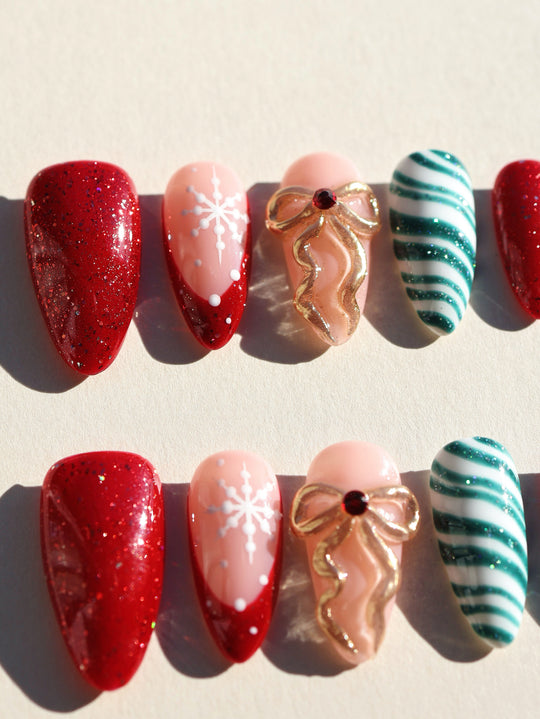 Candy Ribbon press-on nails set with red glitter, white snowflakes, gold bow and green striped tips