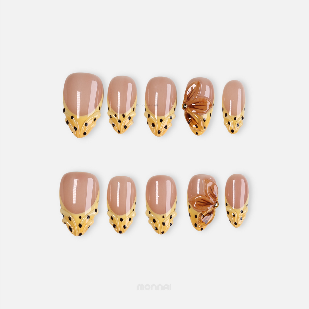 Caramel Dots press-on nails in retroism style, laid out with butter yellow wavy French tips, black polka dots, and amber flower detail.