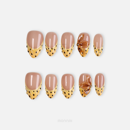 Caramel Dots press-on nails in retroism style, laid out with butter yellow wavy French tips, black polka dots, and amber flower detail.