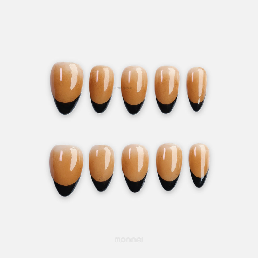 Caramel Edge press-on nails with warm nude base, black French tips, shown laid out in glossy close-up.