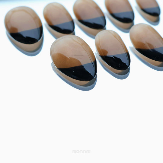 Caramel Edge press-on nails in close-up, showing warm nude bases with crisp black French tips and a glossy shine.