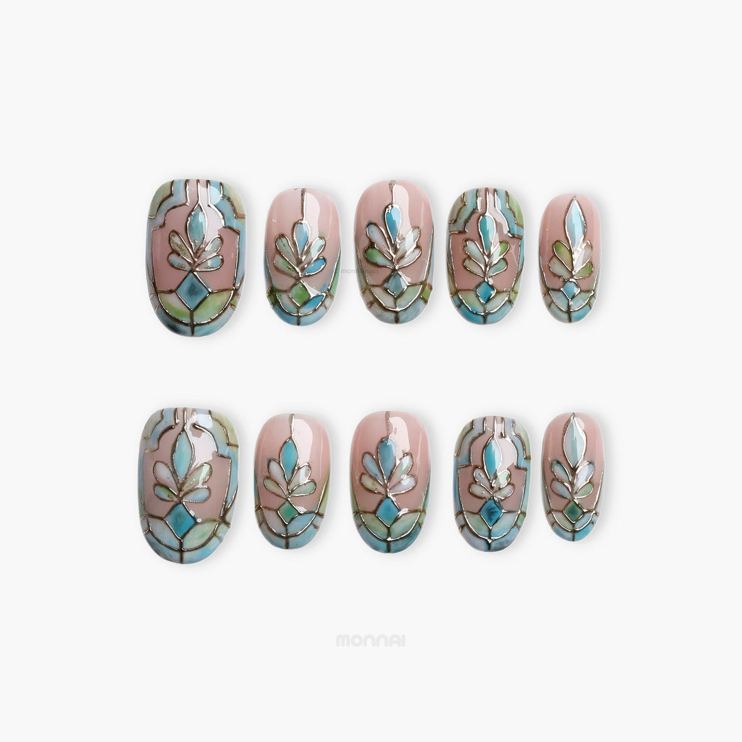 Cathedral Bloom press-on nails laid out in a stained-glass pattern with soft nude, pale blue, and sage tones