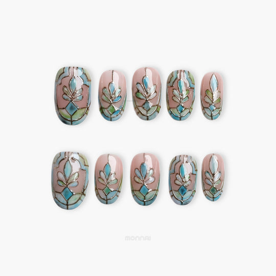Cathedral Bloom press-on nails laid out in a stained-glass pattern with soft nude, pale blue, and sage tones
