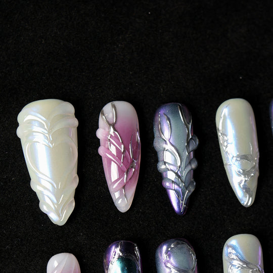 Celestial Aurora press-on nails laid out in close-up, showing iridescent white, violet-blue, and soft pink sculpted chrome details.