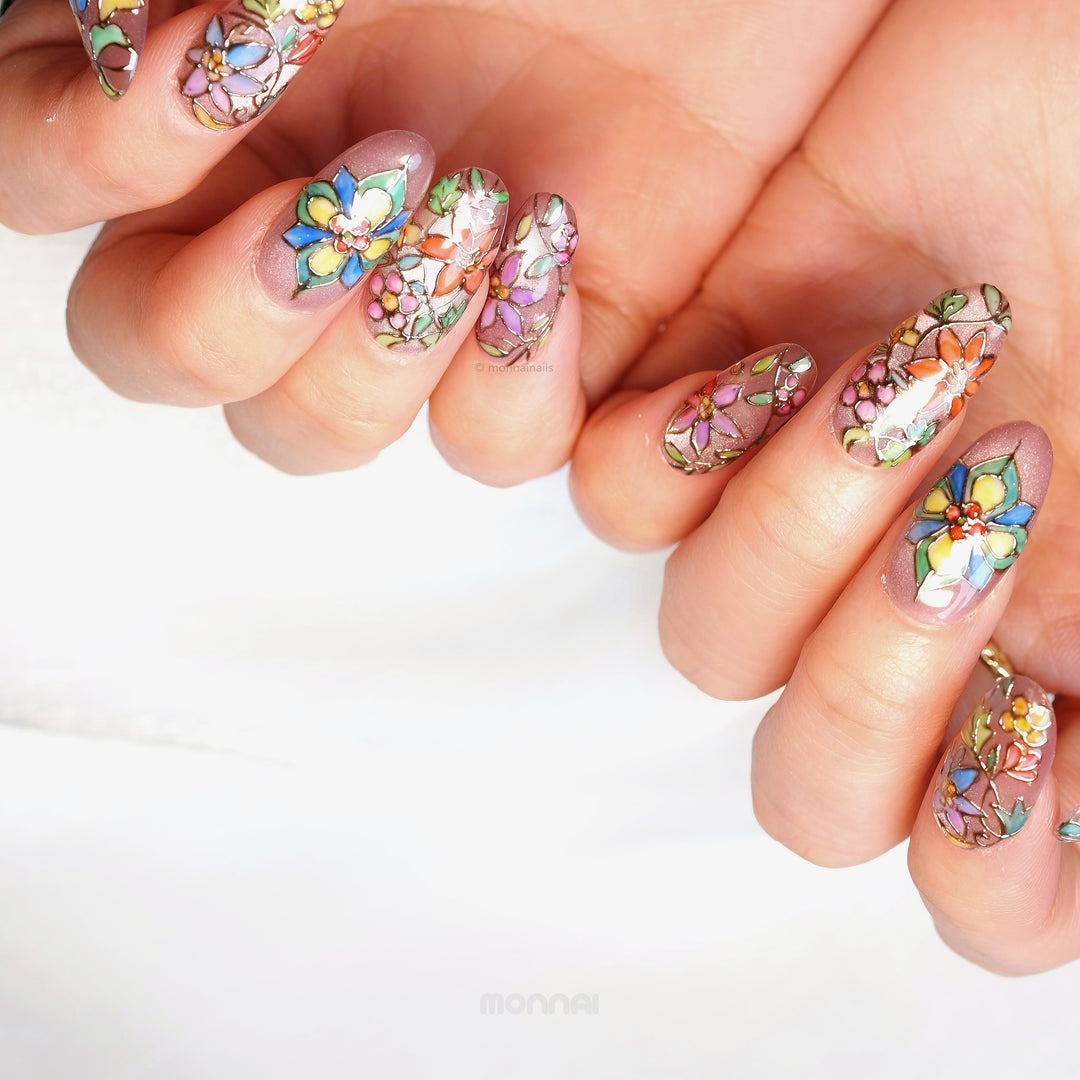 Chapel Garden press-on nails worn on hands, with jeweled floral mosaic details and dark outlines on a shimmering base.