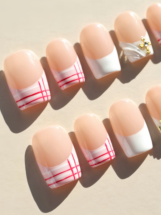 Cherry Check preppy press-on nails with pink-red plaid French tips, shown laid out in a close-up.