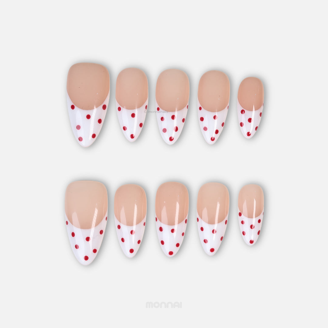 Cherry Pop press-on nails laid out in a clean classic style, with nude pink French tips, red polka dots, and gel-gloss finish.