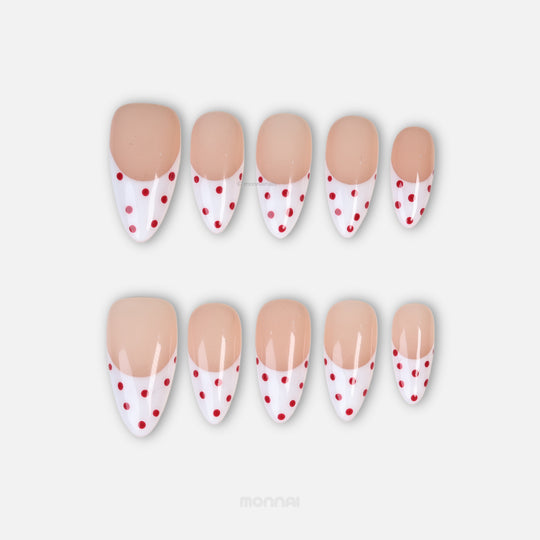 Cherry Pop press-on nails laid out in a clean classic style, with nude pink French tips, red polka dots, and gel-gloss finish.