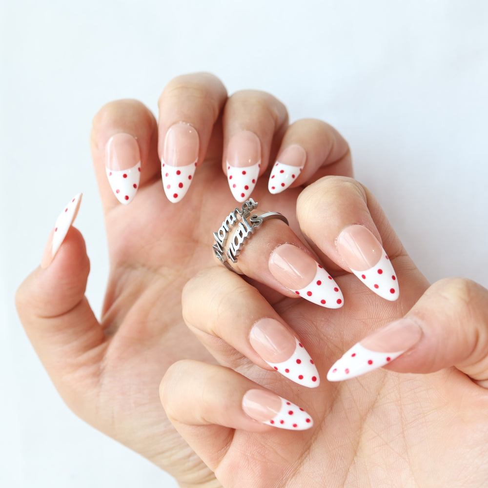 Cherry Pop press-on nails shown worn on hands, with nude pink French tips and red polka dots.