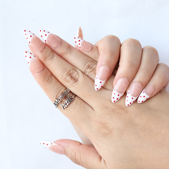 Cherry Pop press-on nails worn on hand, nude pink French tips with red polka dots