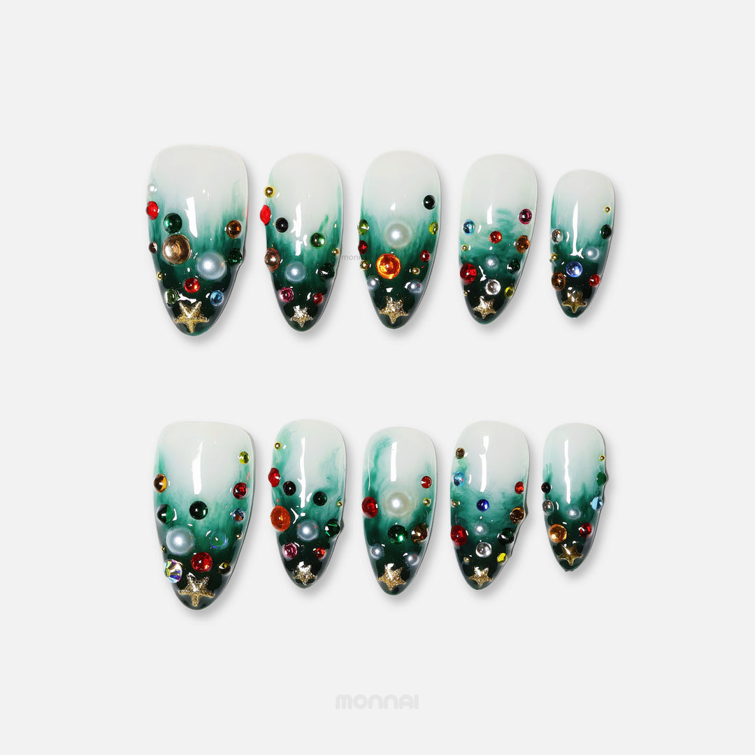 Christmas Tree press-on nails with emerald green gradient, colorful gems, pearls and gold star charms laid out on white