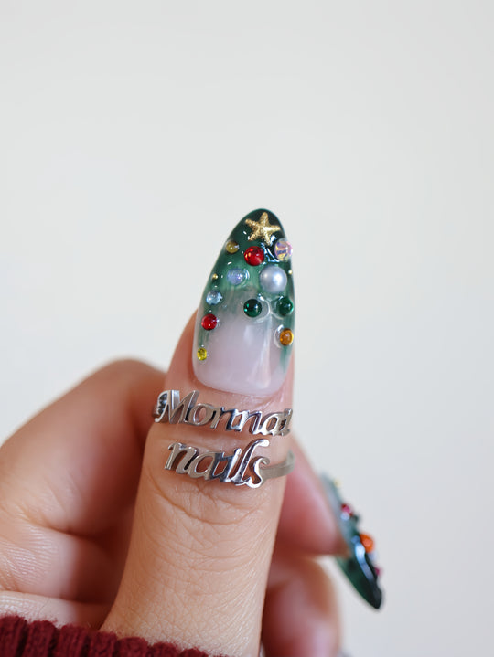 Christmas Tree press-on nails on hand with emerald green gradient, milky white base, rhinestones, pearls and gold star charm