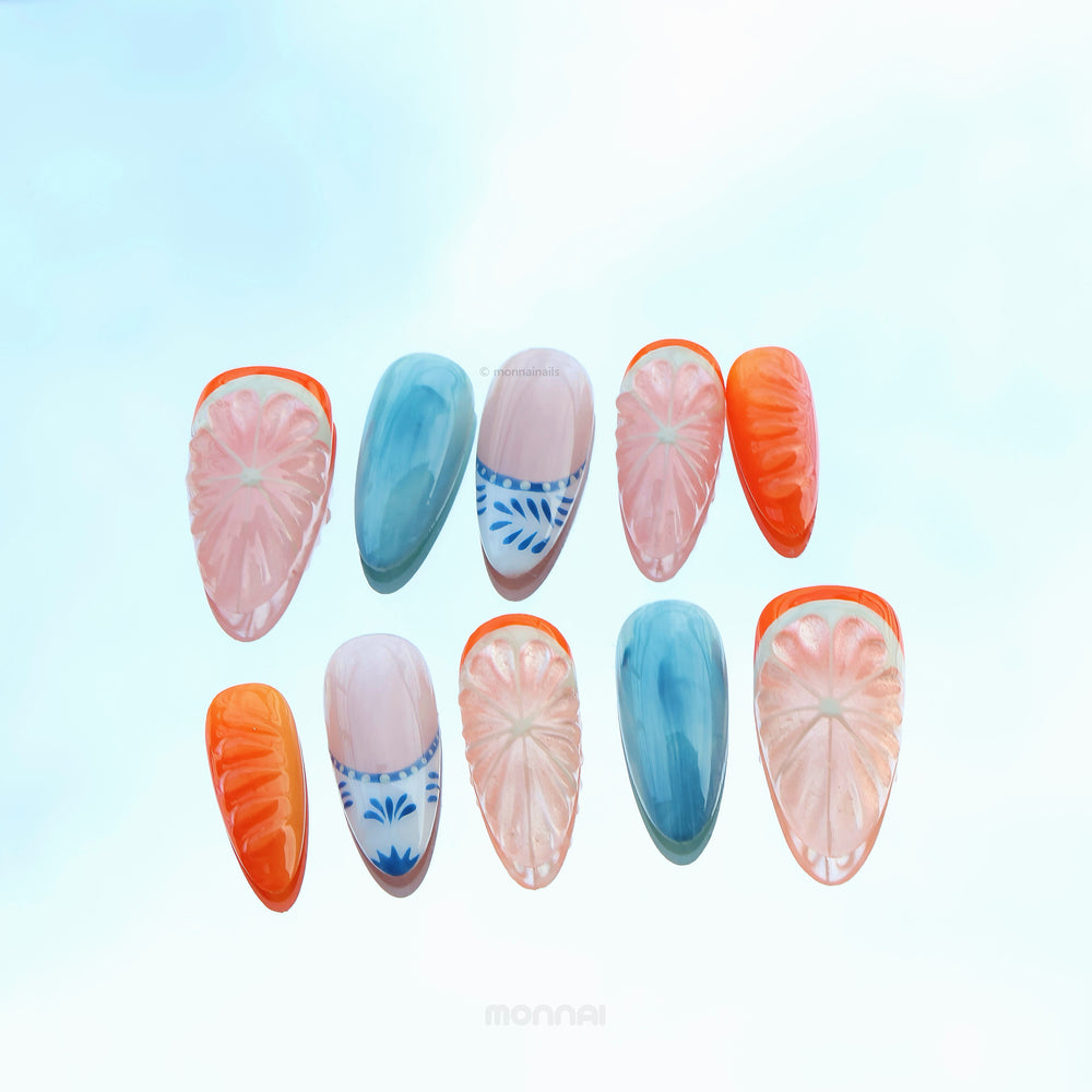 Citrus Porcelain press-on nails laid out, with grapefruit slice details, ocean blue fades, and orange accents.