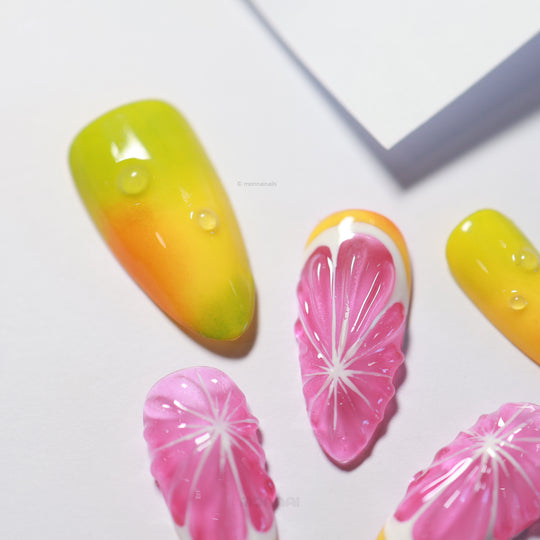 Citrus Splash press-on nails laid out, with glossy yellow-to-green gradients and pink citrus slice details
