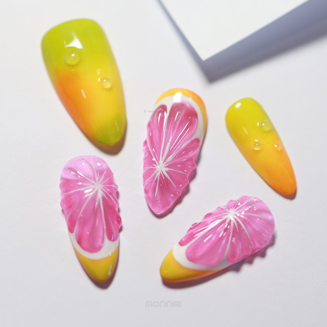 Citrus Splash press-on nails laid out with glossy citrus slice details, yellow-to-green gradients, and pink accents