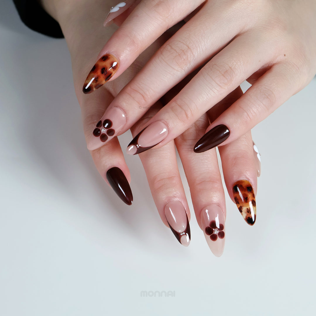 Classic Petals press-on nails on hands, with beige and brown tones, tortoiseshell accents, and simple flower details.