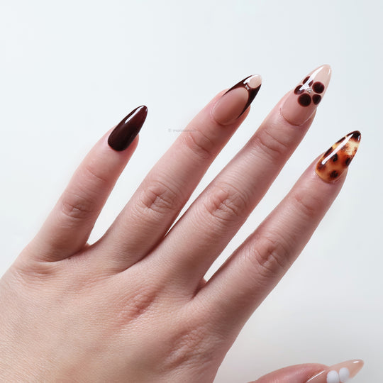 Classic Petals press-on nails on hand with beige and brown tones, glossy tortoiseshell accents, and a simple sculpted flower