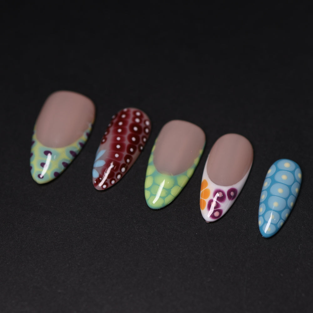 Coral Reef press-on nails laid out with abstract crocodile-skin patterns and glossy colorful French tips.