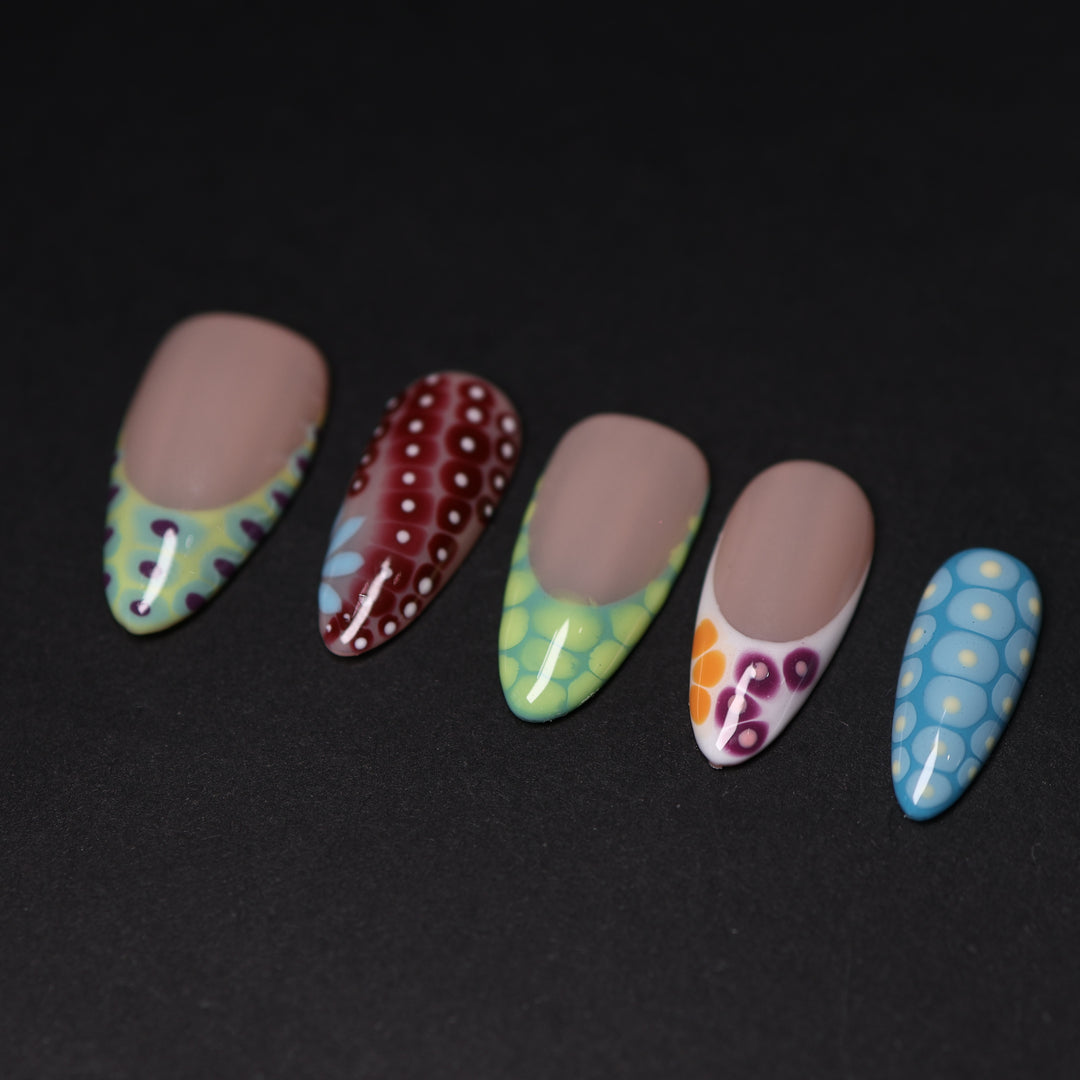 Coral Reef press-on nails laid out with abstract crocodile-skin patterns and glossy colorful French tips.