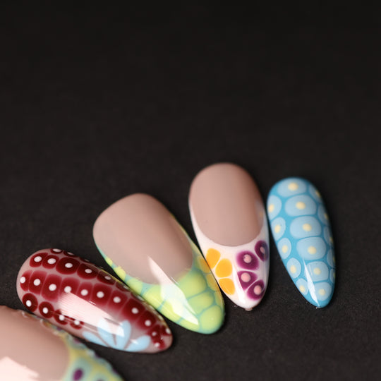 Coral Reef press-on nails in close-up, showing abstract croc-textured tips in red, blue, and yellow with glossy finish.