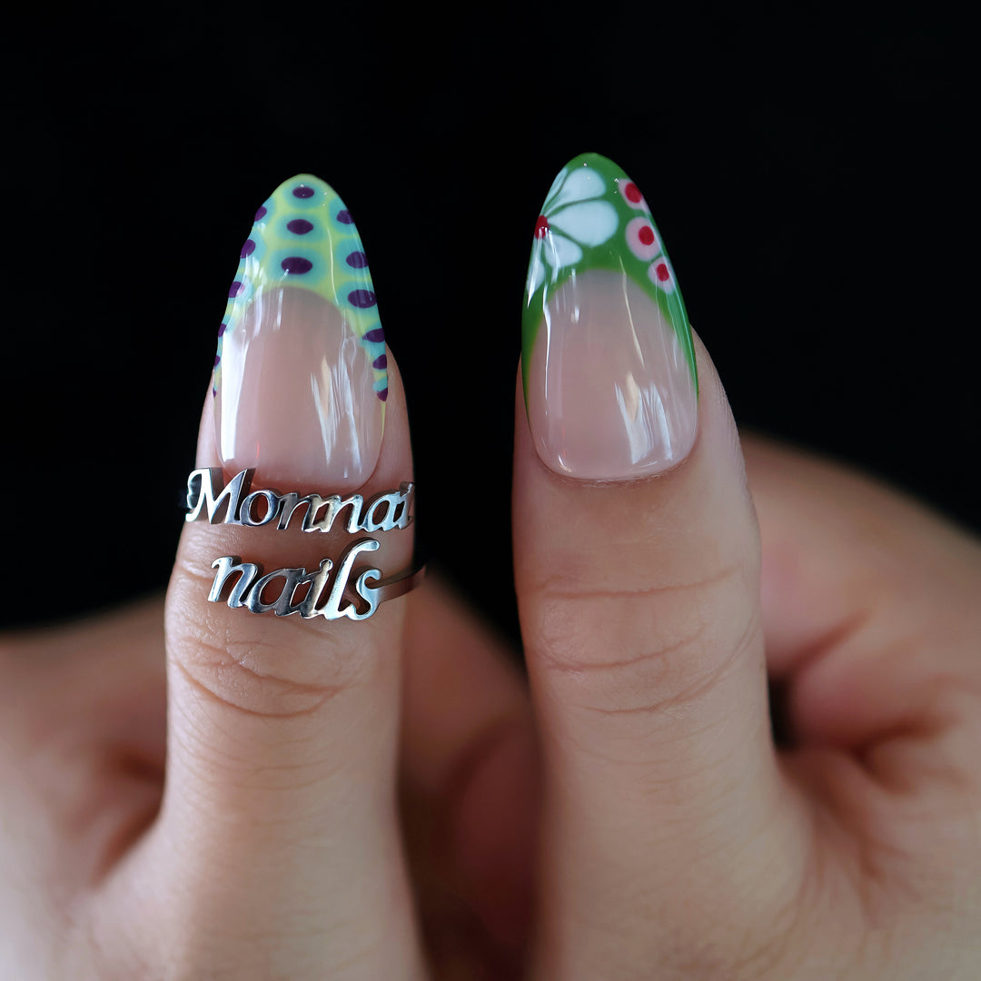 Coral Reef press-on nails on hands, with abstract green tips, purple dots, and glossy full-cover color.