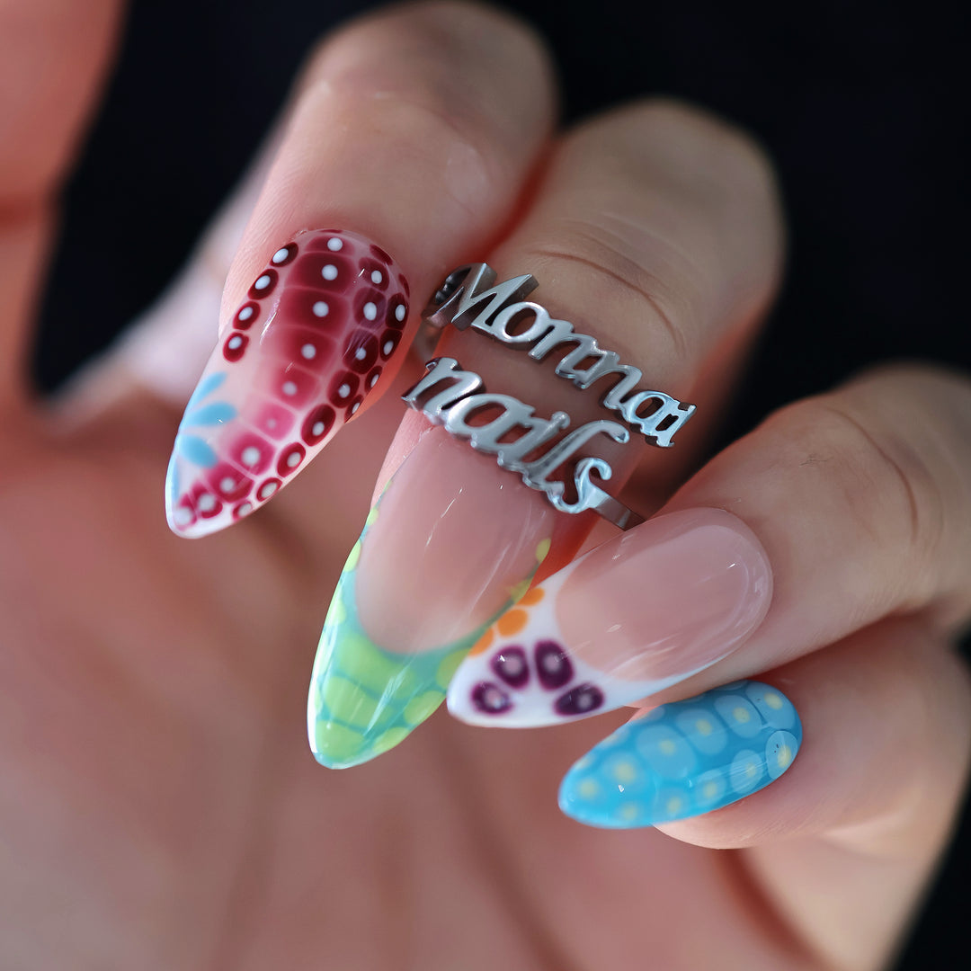 Coral Reef press-on nails worn on hand with glossy abstract coral-inspired dotted tips and colorful patterns