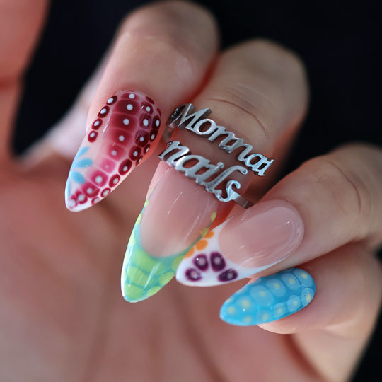 Coral Reef press-on nails worn on hand with glossy abstract coral-inspired dotted tips and colorful patterns