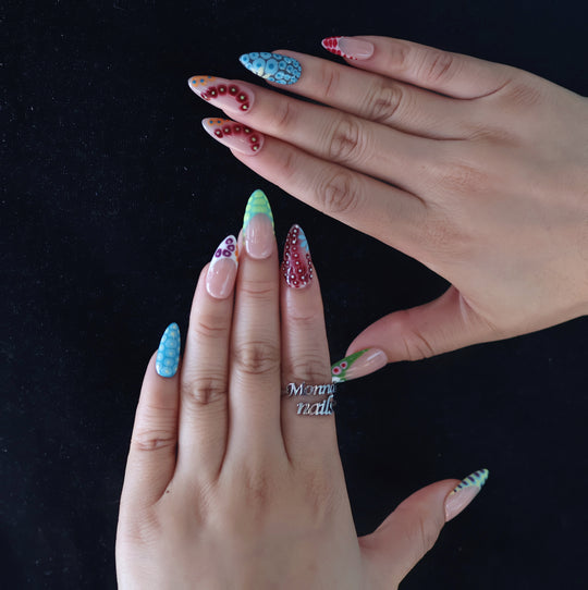 Coral Reef press-on nails shown on hands with colorful abstract blooming gel patterns and glossy textured French tips.