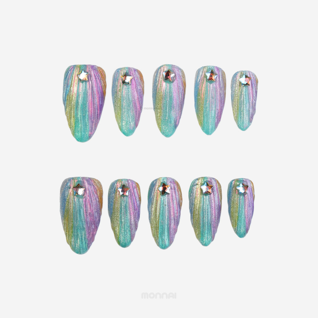Cosmic Glow press-on nails laid out with iridescent teal, pink and gold shimmer, 3D seashell texture and star rhinestones.