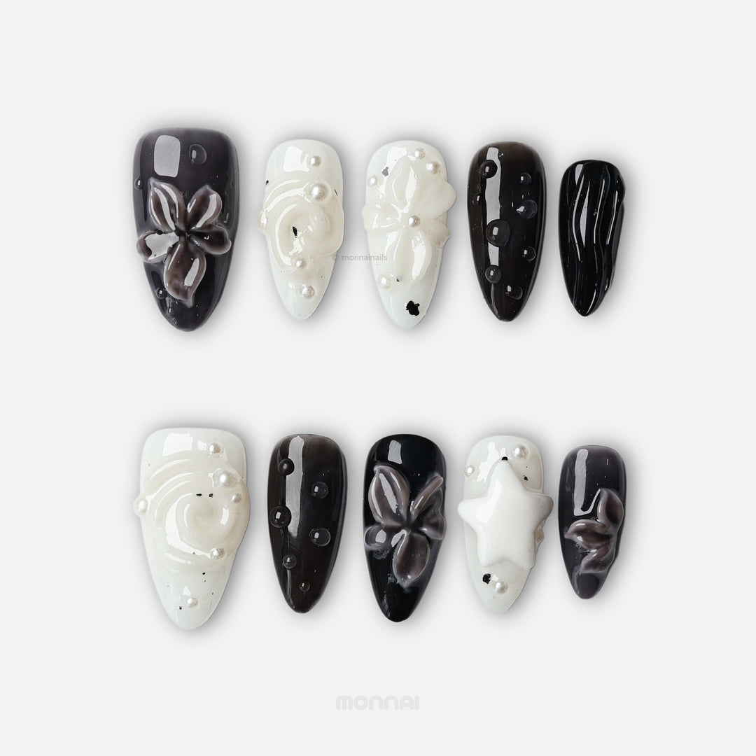 Cream Puff press-on nails in black and milky white, featuring glossy 3D flowers, pearls, and raised star details