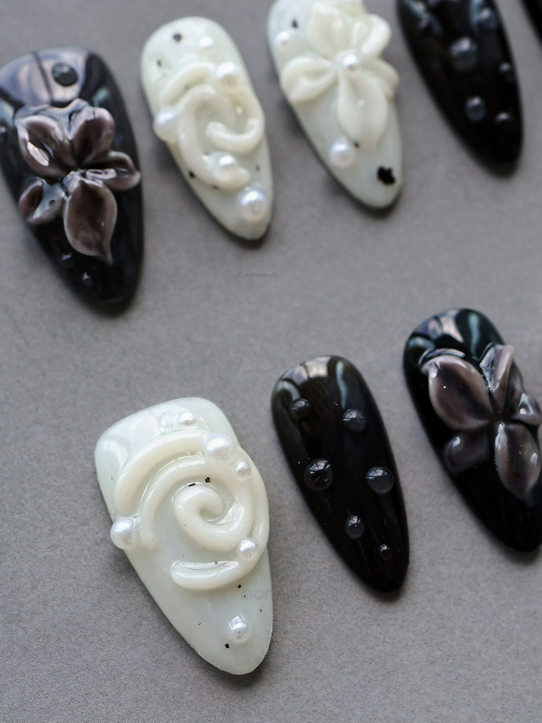 Cream Puff press-on nails laid out in glossy black and milky white, with 3D flowers, pearls, and star accents.