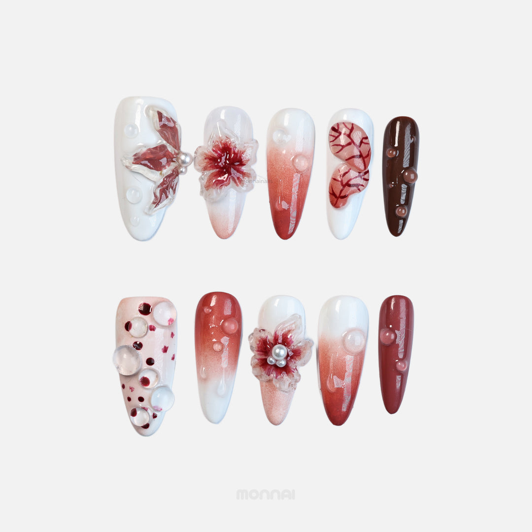 Crimson Bloom press-on nails laid out with blood red ombre, vein details, translucent flowers, and clear water drops