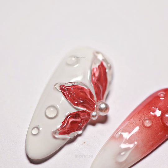Crimson Bloom press-on nails laid out in close-up, with blood red ombre, translucent 3D flower and clear water drop details.