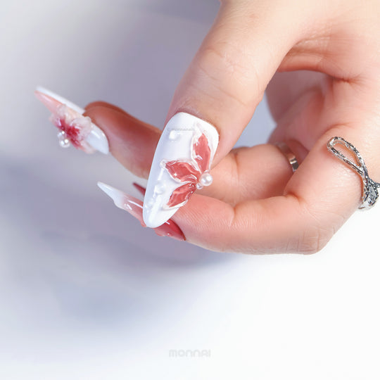 Crimson Bloom press-on nails worn on hand, white base with crimson floral petals and pearl accents
