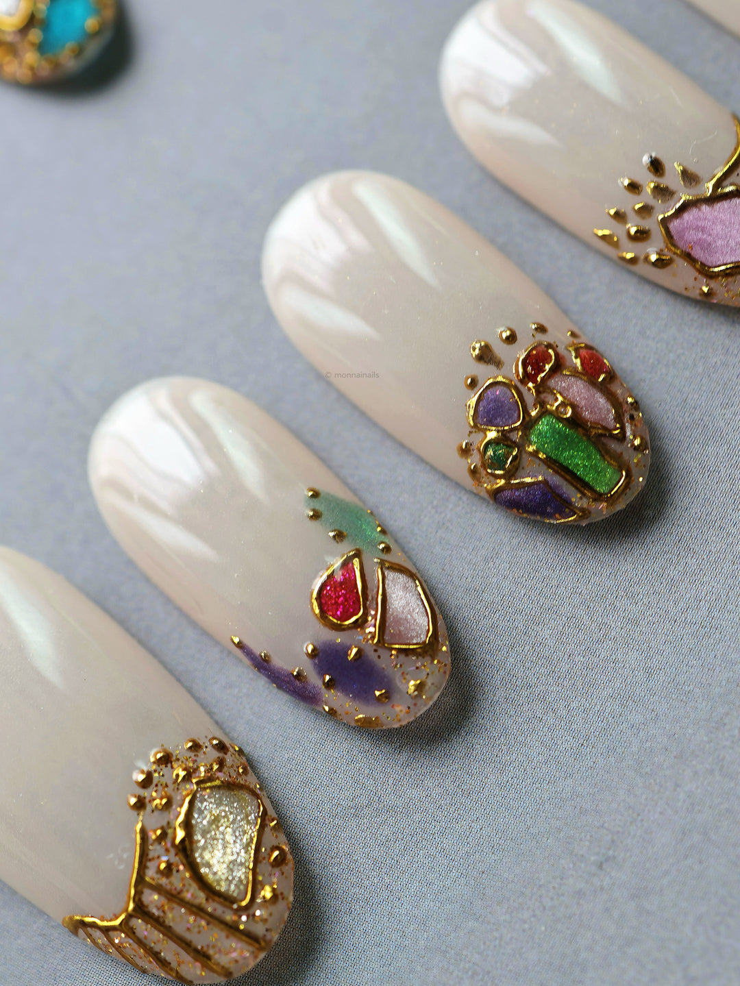 Crown Jewels press-on nails with sheer nude base, mosaic-style accents, and fine gold outlining in close-up
