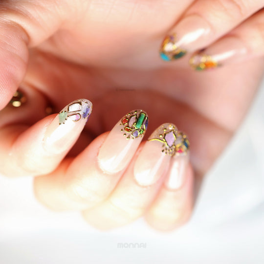 Crown Jewels press-on nails on hand with sheer nude base, mosaic accents, and fine gold outlining