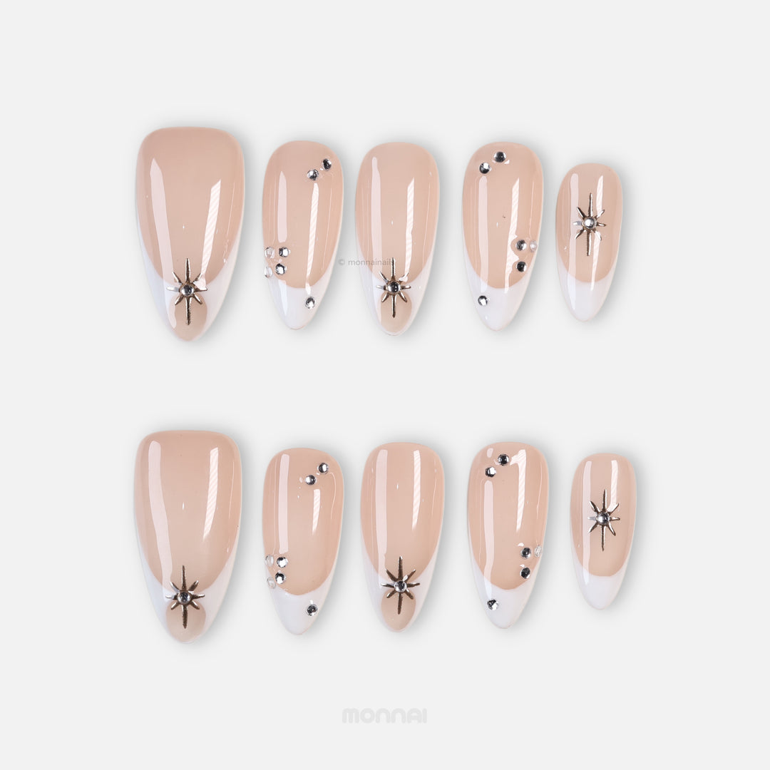 Crystal Bite press-on nails in modern French manicure style with nude bases, white tips, and silver starburst charms