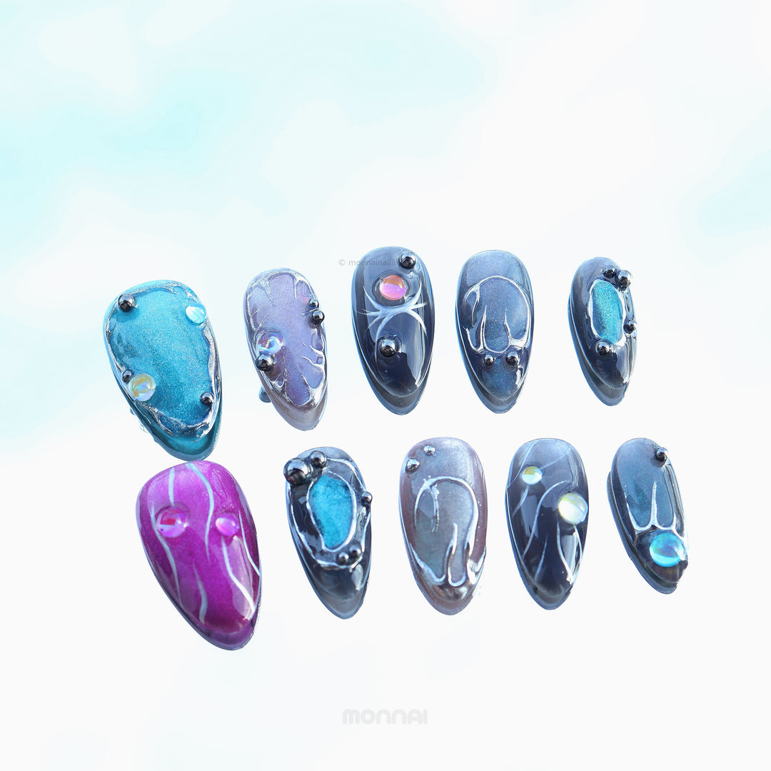 Cyber Galaxy press-on nails laid out with cosmic cat-eye shimmer, chrome details, and glossy celestial accents