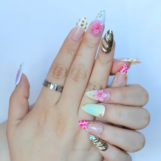 Cyber Sakura press-on nails worn on hands, with pastel ombré, pink 3D floral details, gold studs, and silver chrome accents.