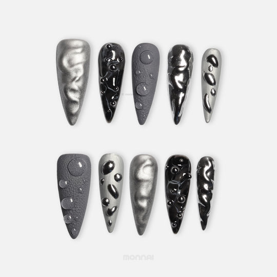 Dark Moon press-on nails laid out in silver, charcoal, and black with crater-like texture and raised gel droplets.
