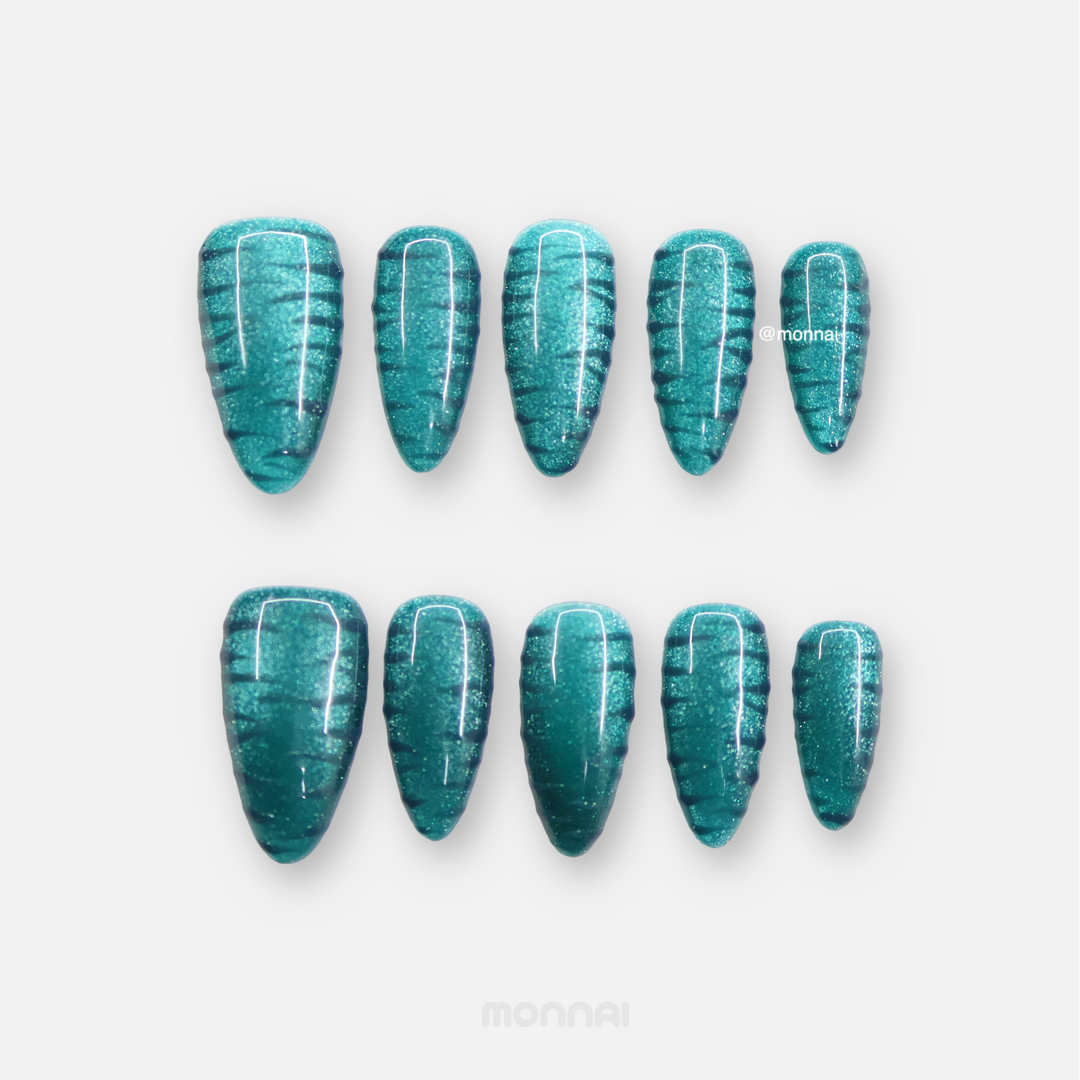 Deep Sea press-on nails laid out in teal cat-eye with raised zebra texture and glossy finish