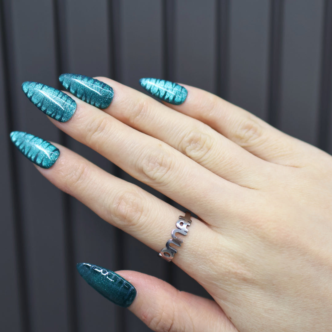 Deep Sea press-on nails on hand, teal cat-eye finish with zebra texture and glossy shine