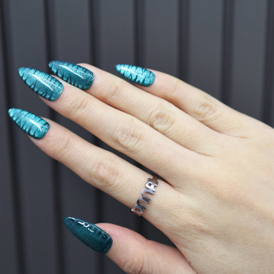 Deep Sea press-on nails on hand, teal cat-eye finish with zebra texture and glossy shine