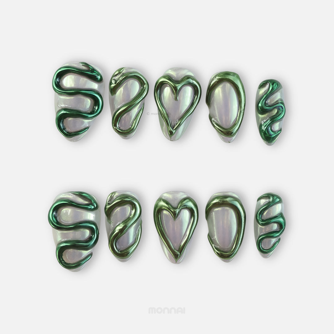 Emerald Heart press-on nails laid out, pearlescent aurora base with raised liquid metal green chrome hearts and serpentine motifs.