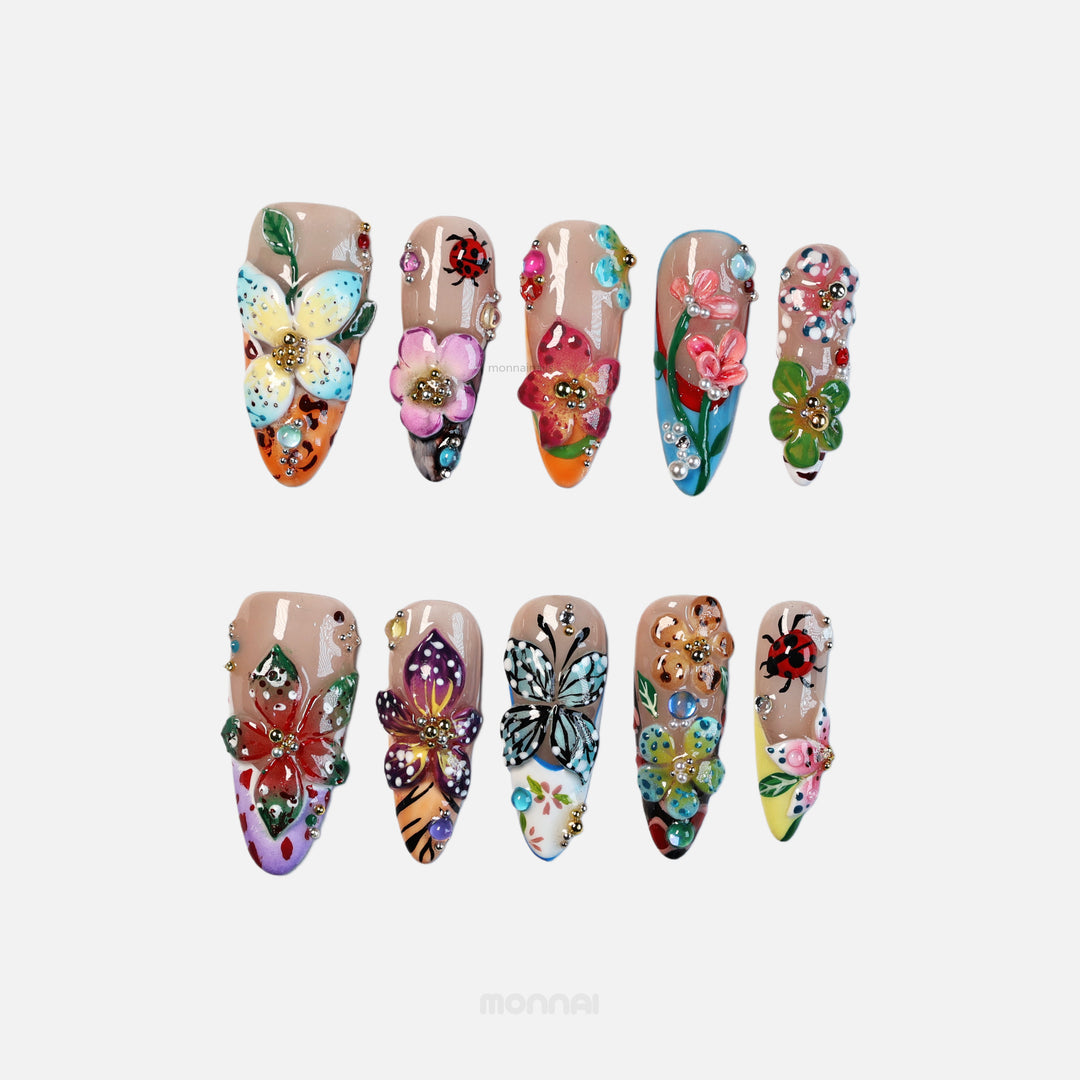 Enchanted Garden press-on nails with hand-painted flowers, butterflies, and colorful 3D botanical details shown in a flat lay.